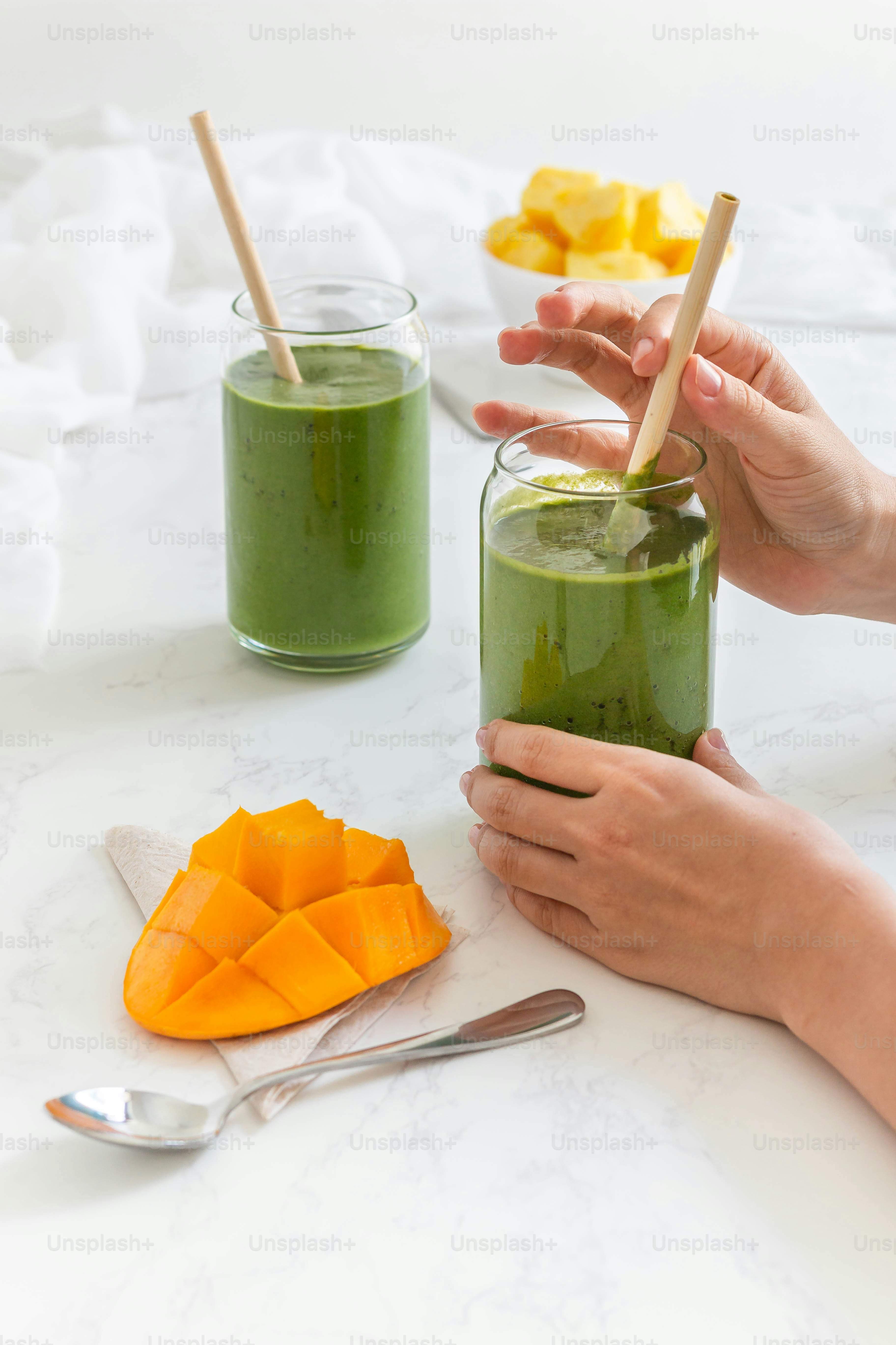 a person holding a glass of green smoothie