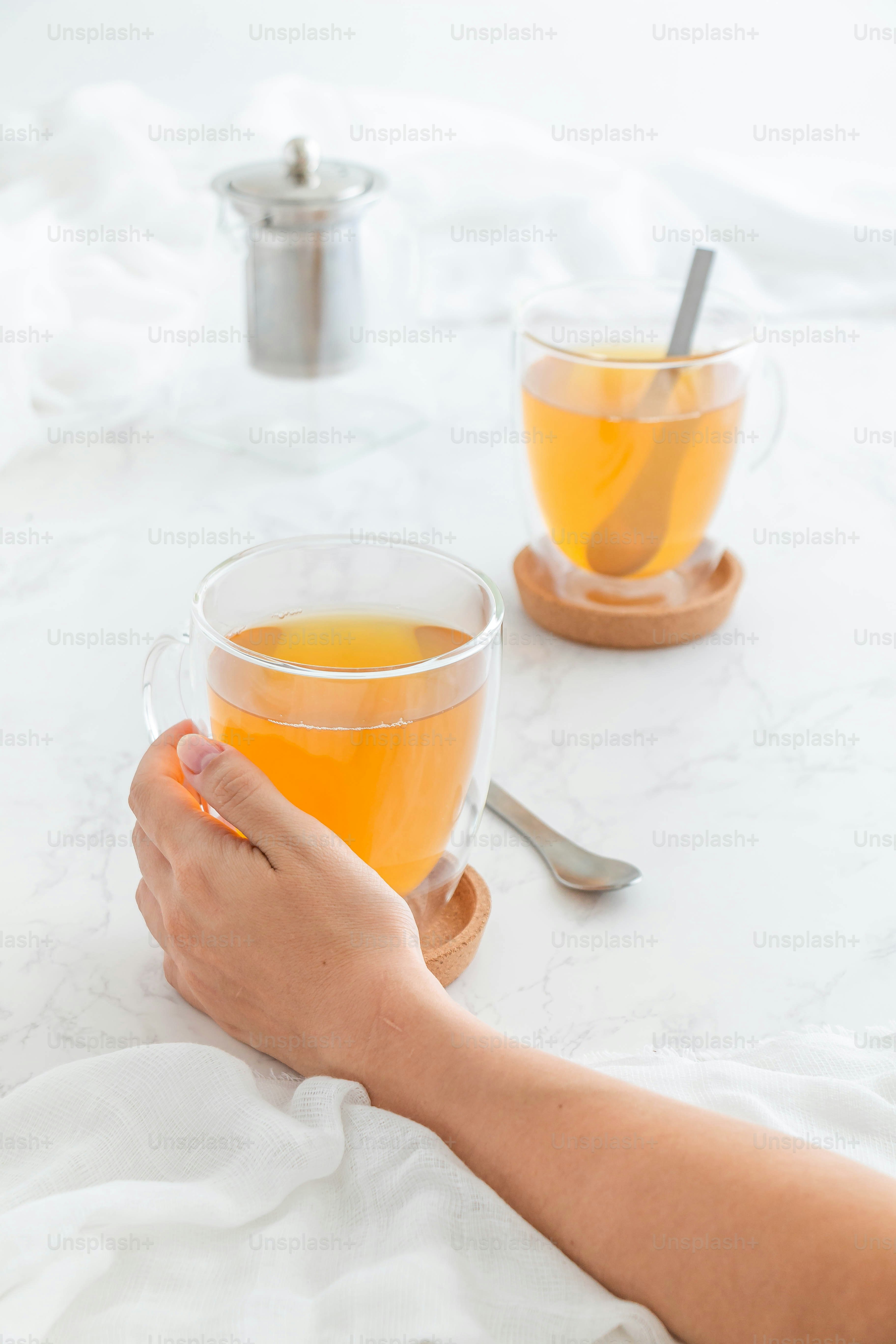 A person holding a cup of tea on a table photo – Healthy drink Image on ...