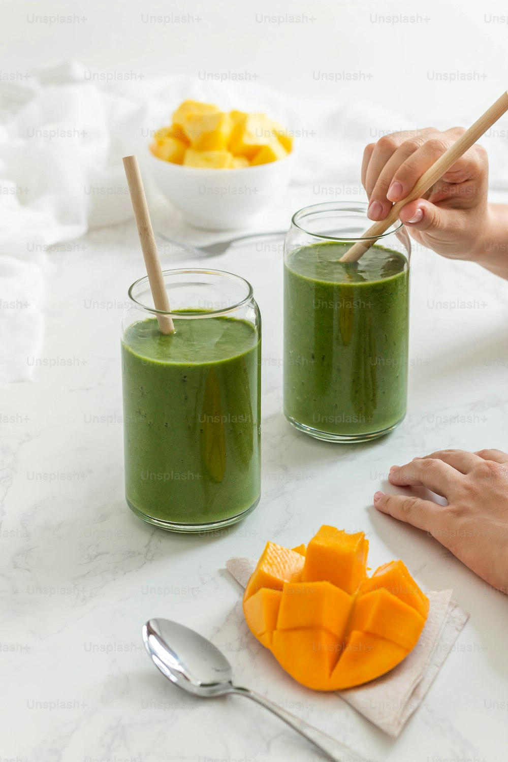 two glasses of green smoothie on a white table