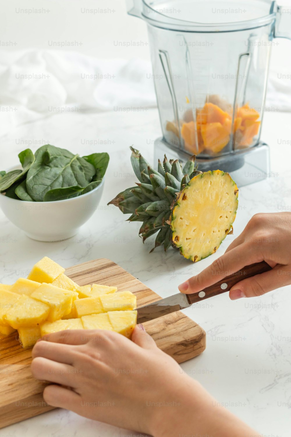 a person cutting up a pineapple on a cutting board