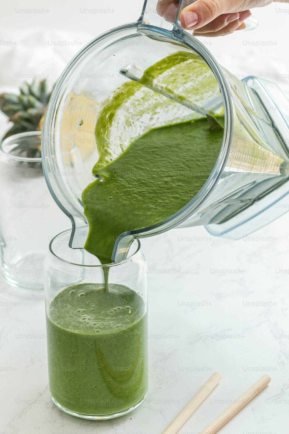 a person pouring a green smoothie into a glass