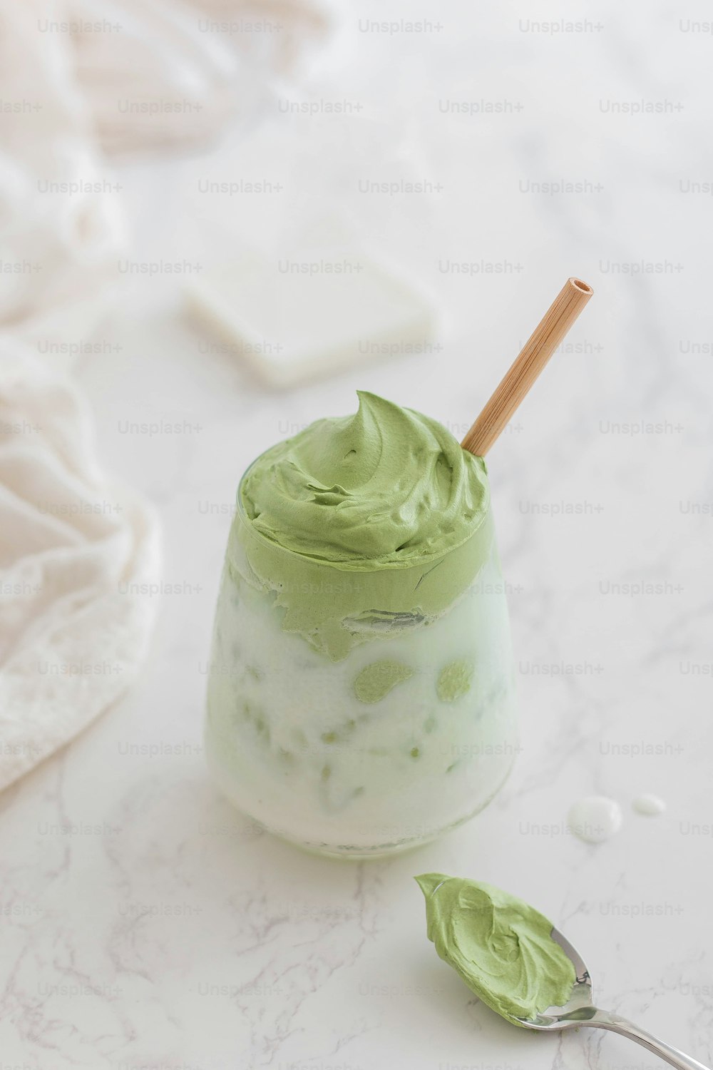 a cup of green cream with a spoon next to it