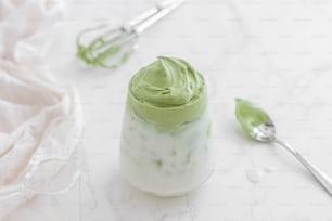 a small jar of green whipped cream next to a spoon