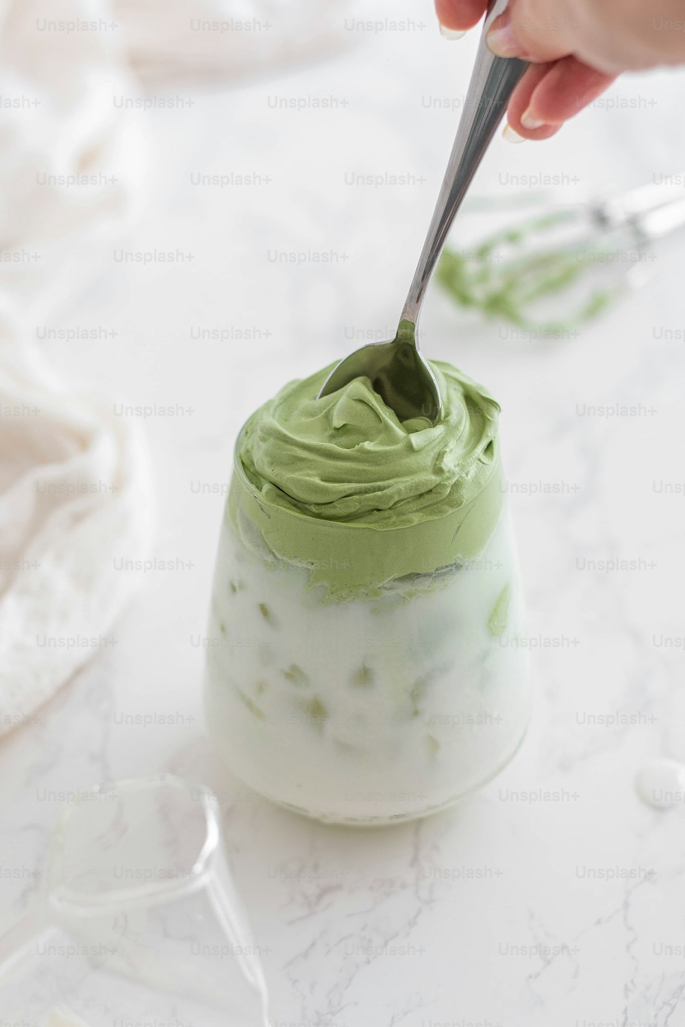 a person holding a spoon over a jar of green cream