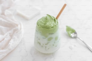 a green drink with whipped cream and a spoon
