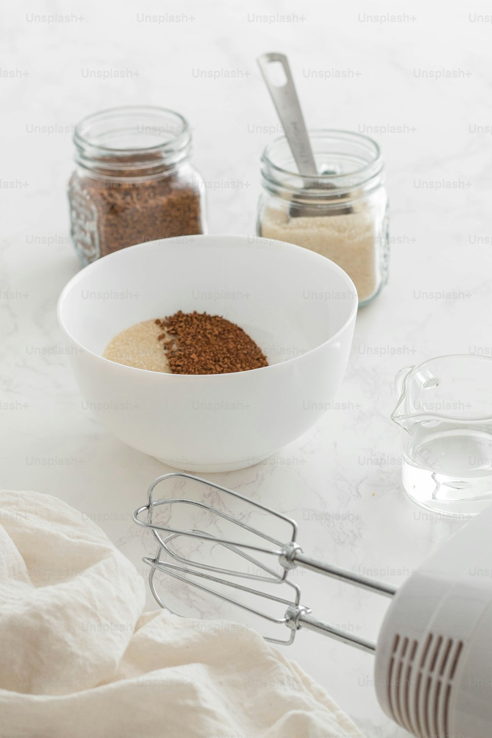 a white bowl filled with spices next to a whisk and a whis
