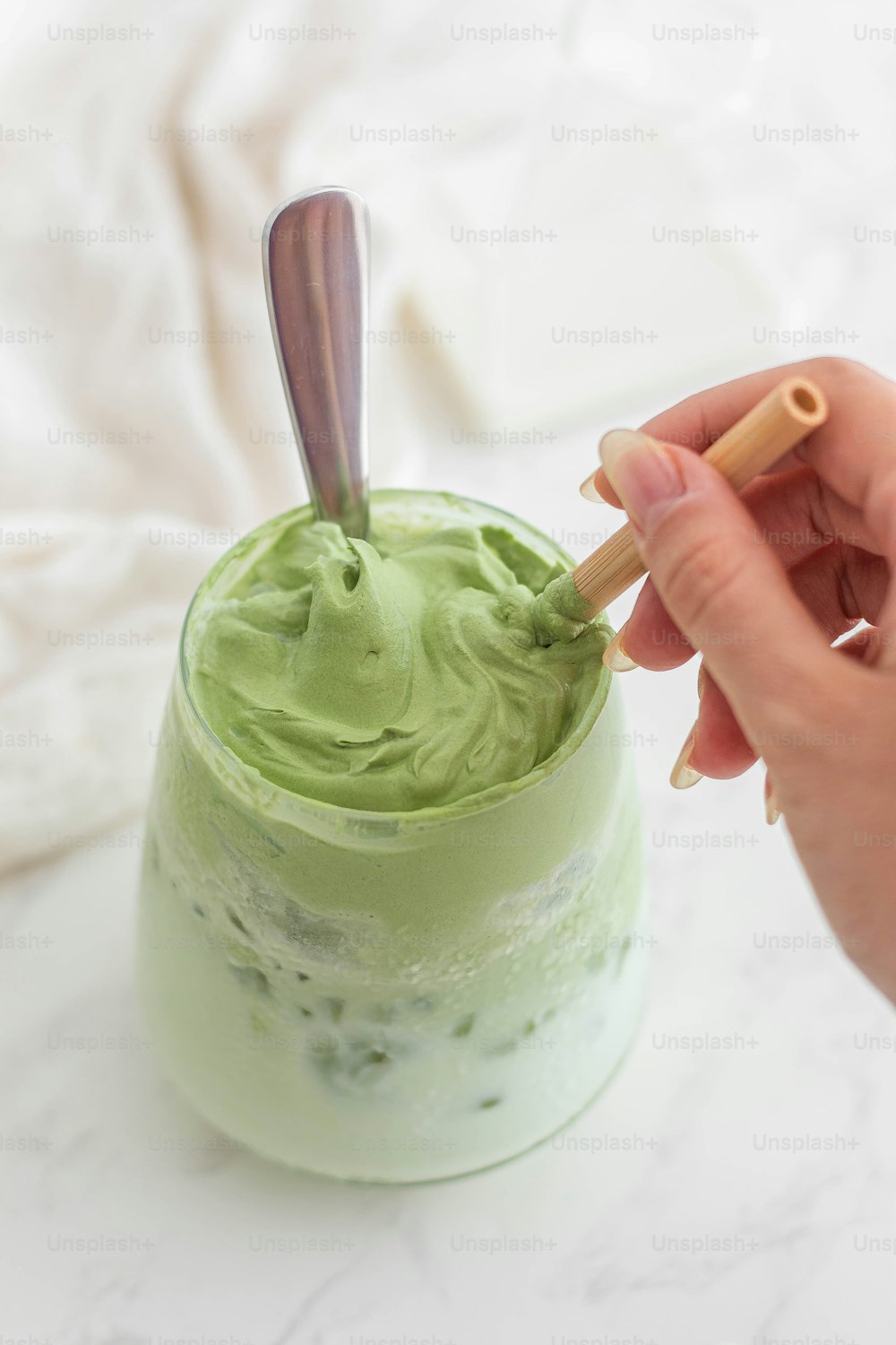 a hand holding a wooden spoon over a green smoothie