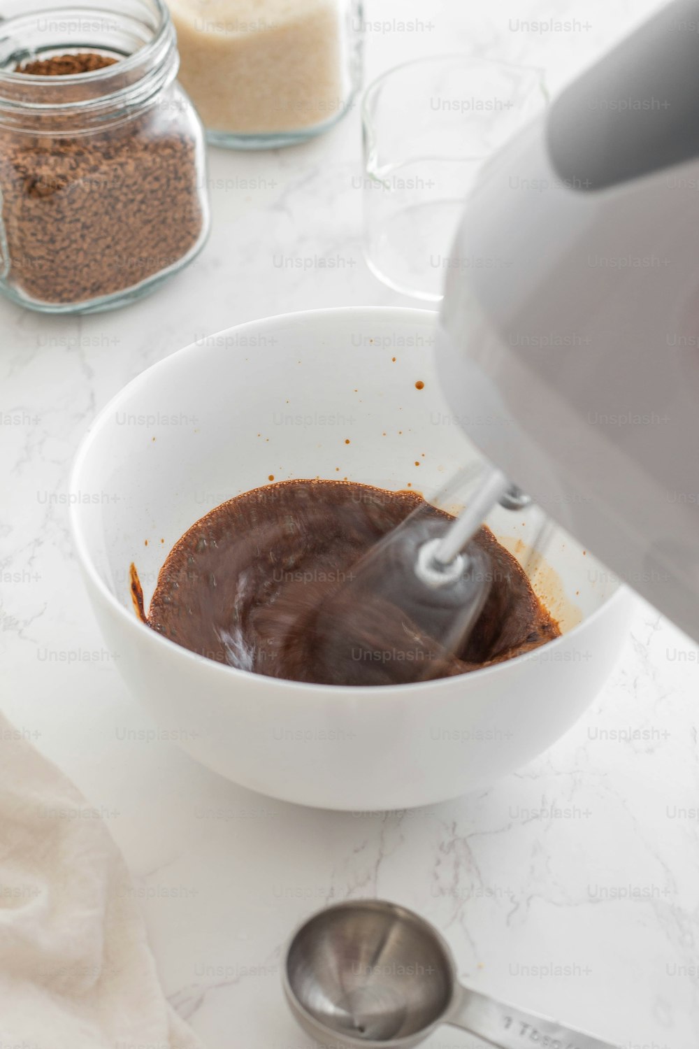 a white bowl filled with brown liquid next to a blender