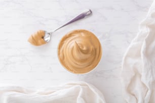 a bowl of peanut butter next to a spoon
