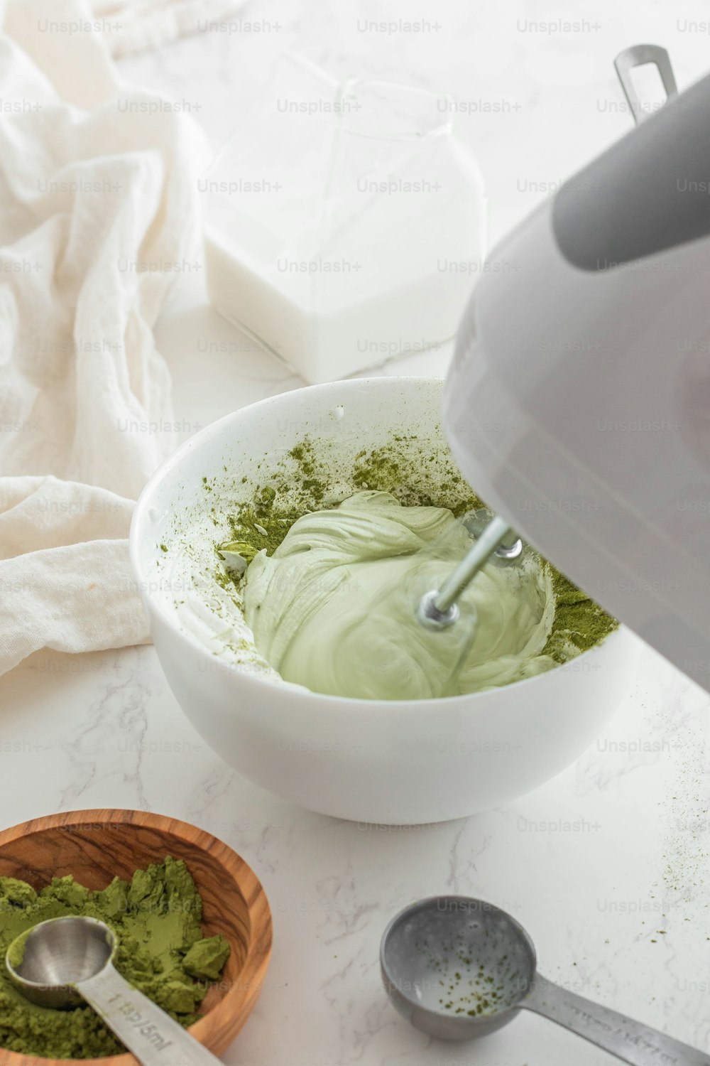 a white bowl filled with green powder next to a spoon