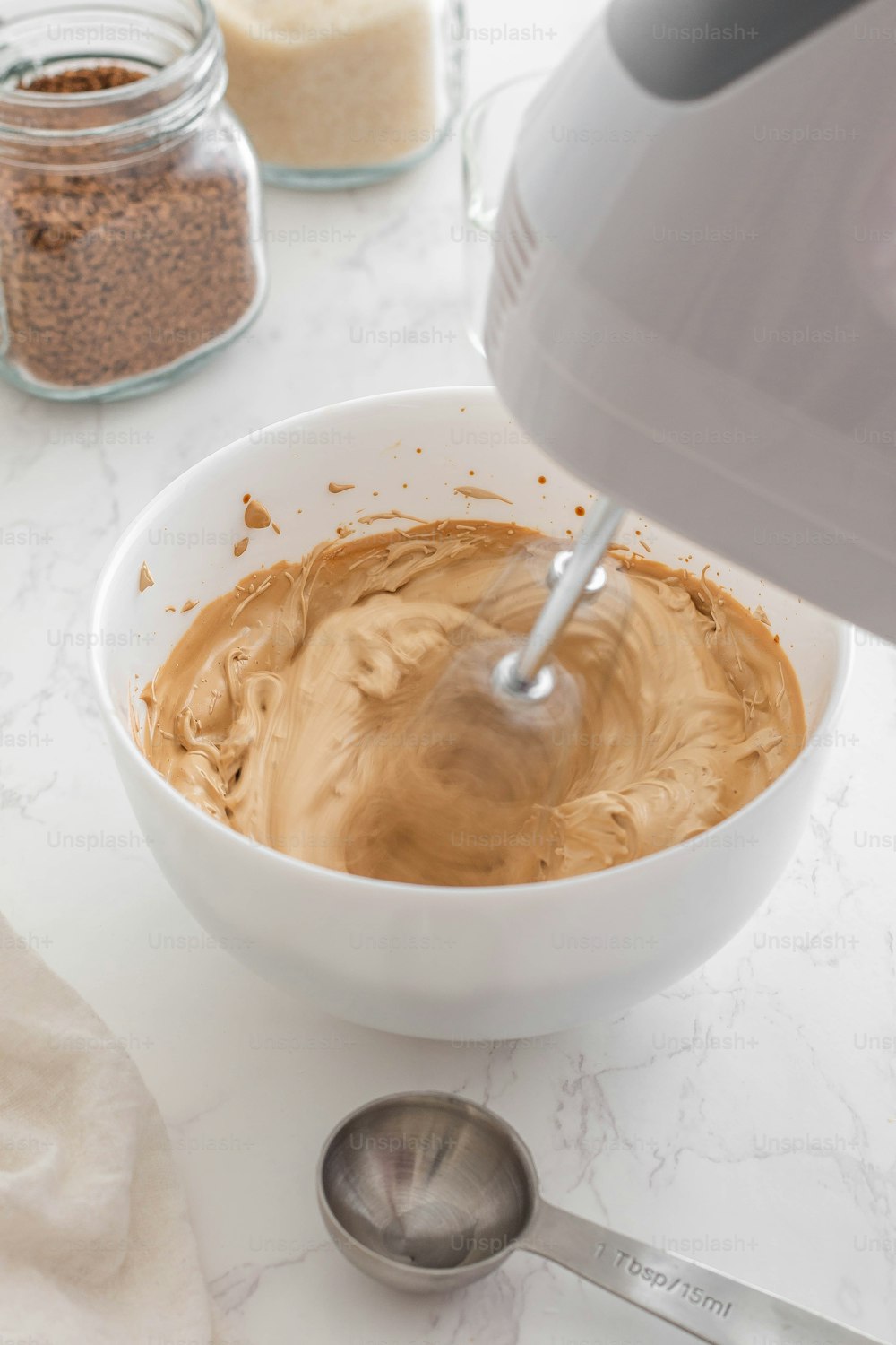 a bowl of peanut butter with a mixer in it