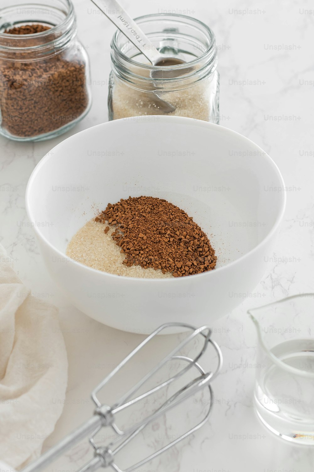 a white bowl filled with spices next to a whisk