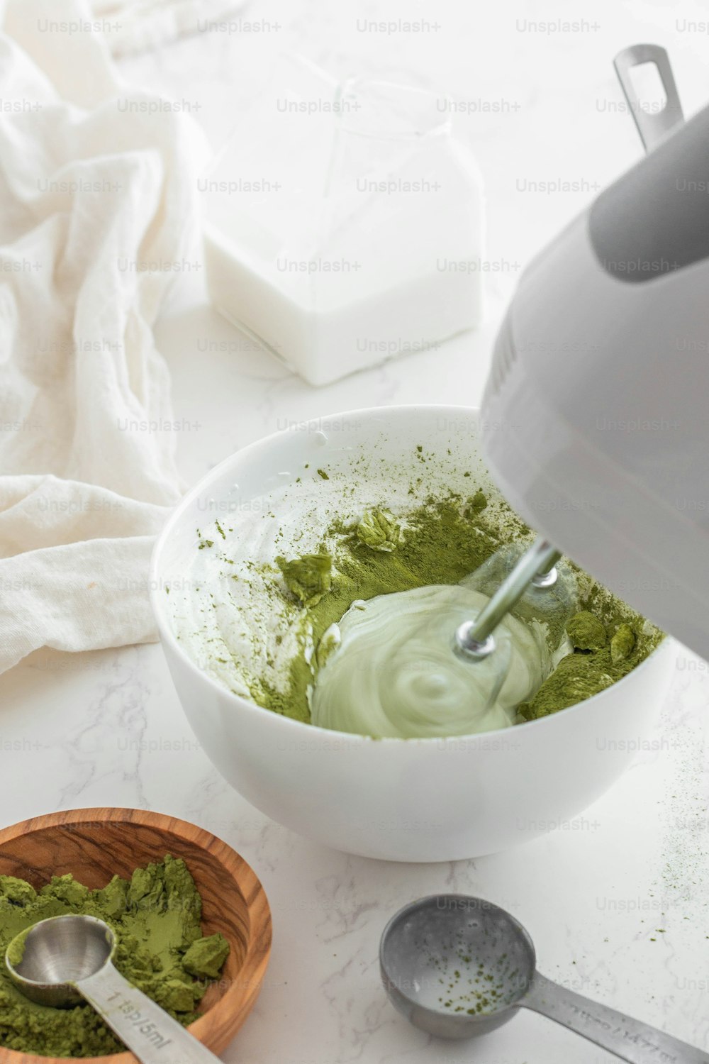 a bowl filled with green powder next to a spoon