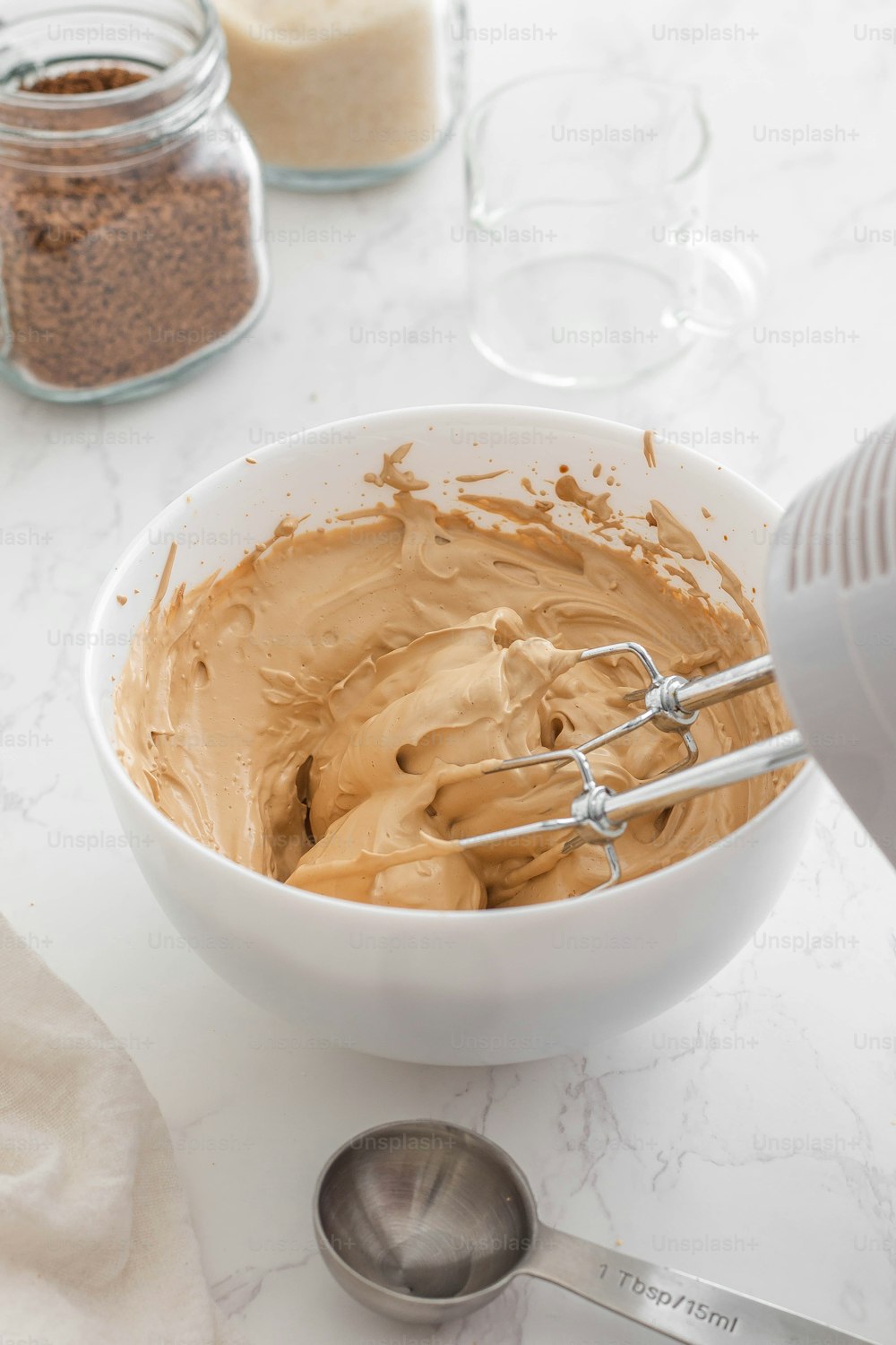 a bowl of peanut butter with a whisk in it