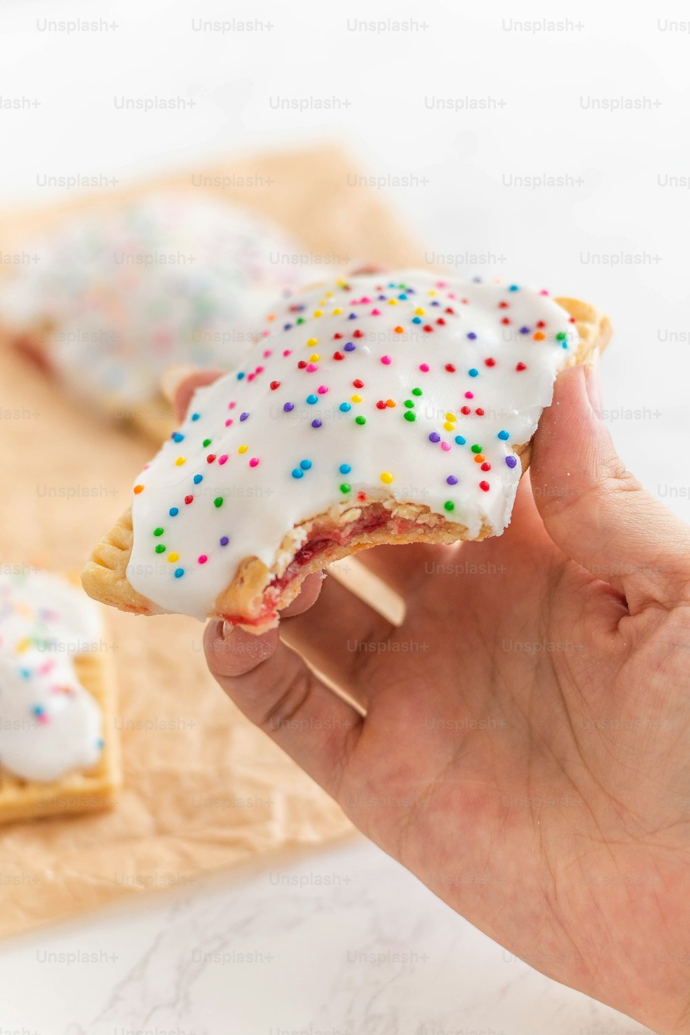 a hand holding a half eaten donut with sprinkles