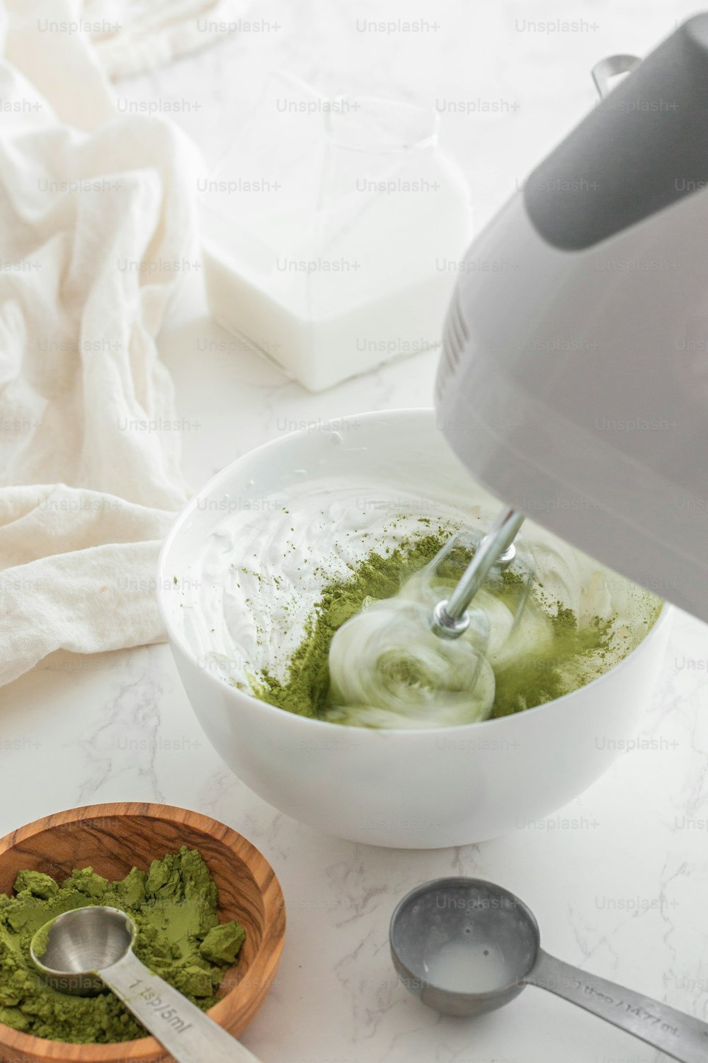 a white bowl filled with green liquid next to a wooden bowl filled with cucum