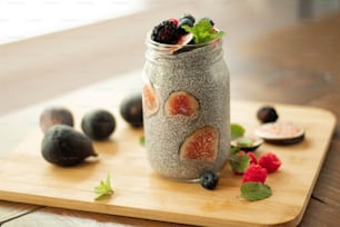 a jar of chia seed pudding with fruit on a cutting board
