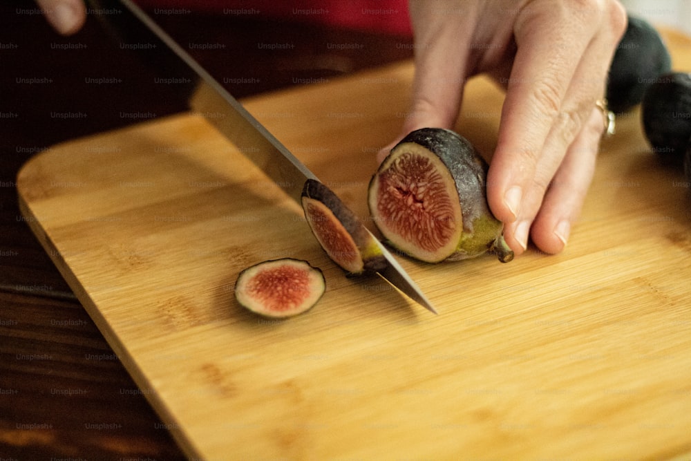 a person cutting up a piece of fruit on a cutting board