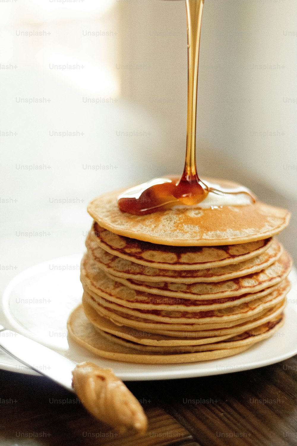 a stack of pancakes with syrup being poured on top
