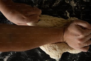 a person is kneading dough into a ball