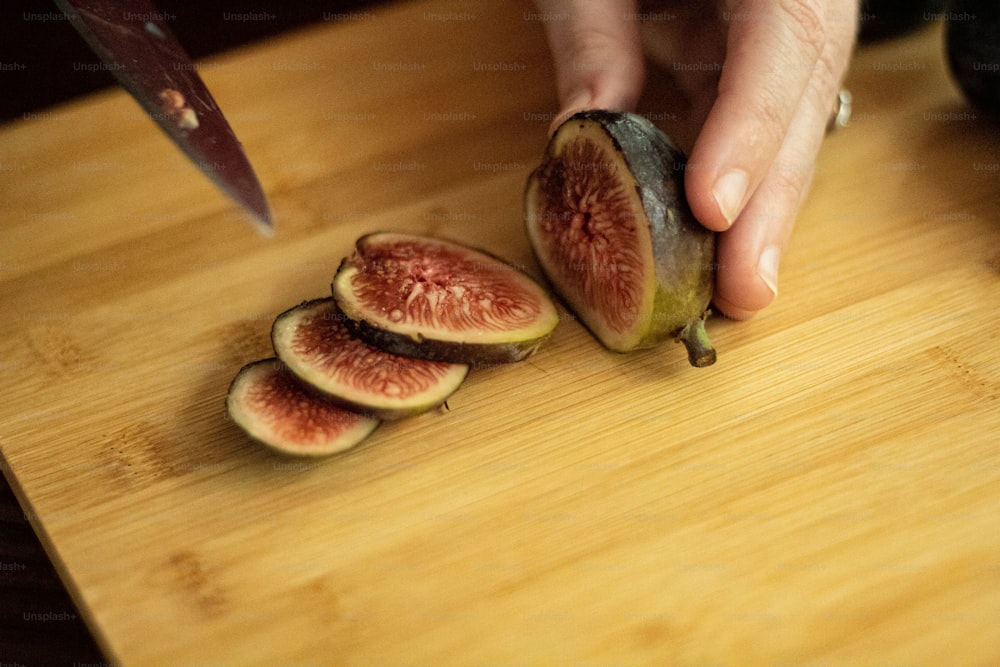 una persona cortando una pieza de fruta en una tabla de cortar