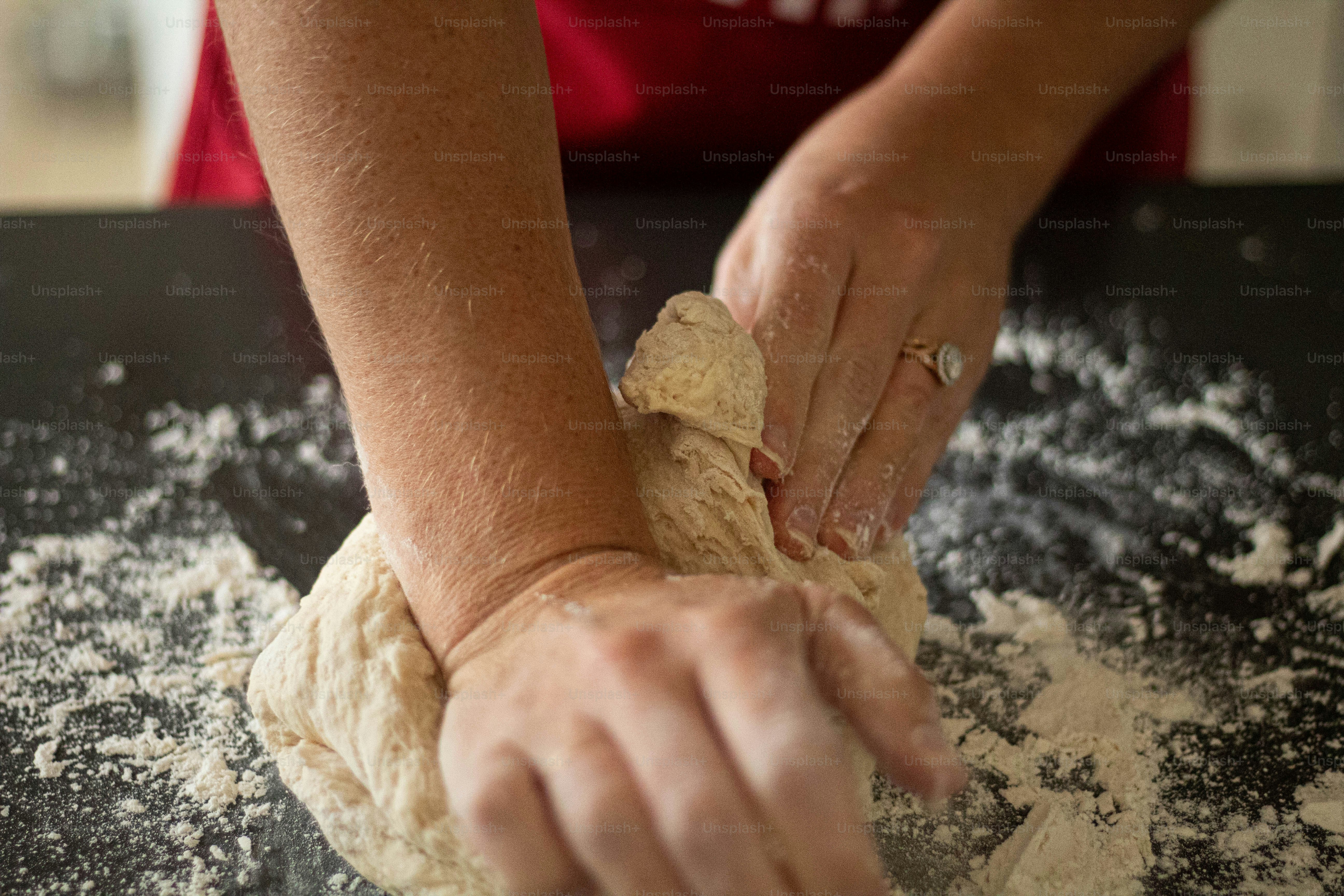 une personne pétrissant de la pâte sur une table