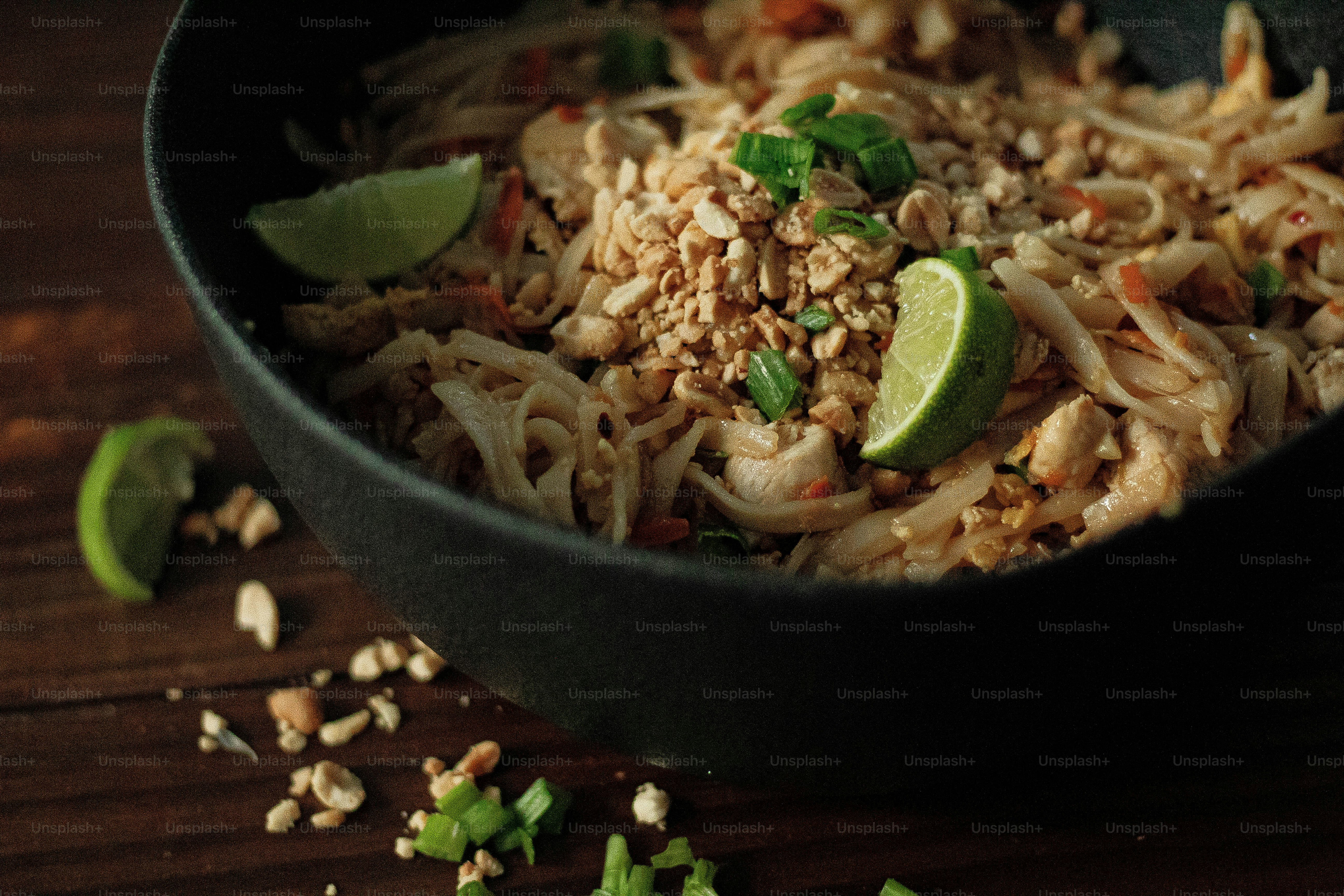 a bowl filled with noodles and vegetables on a wooden table