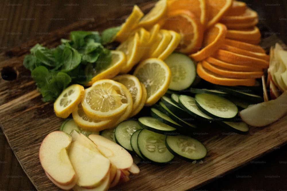 a cutting board topped with sliced up oranges and cucumbers