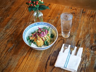 a bowl of food and a glass of water on a table