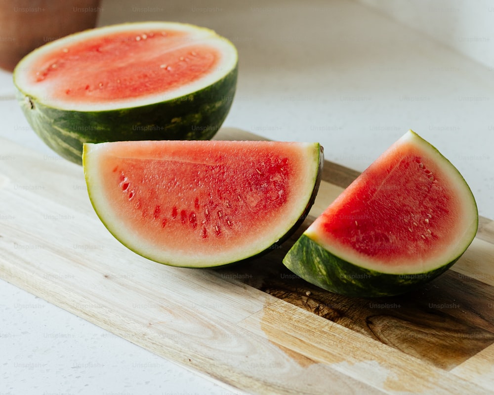 three slices of watermelon on a cutting board