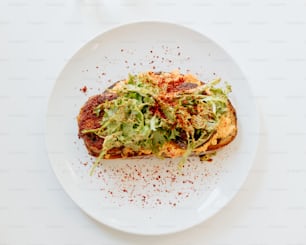 a white plate topped with a slice of pizza covered in lettuce