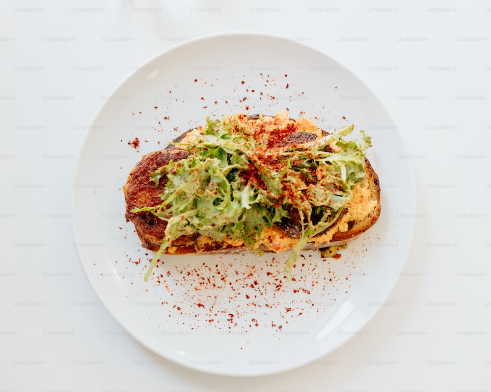 a white plate topped with a slice of pizza covered in lettuce