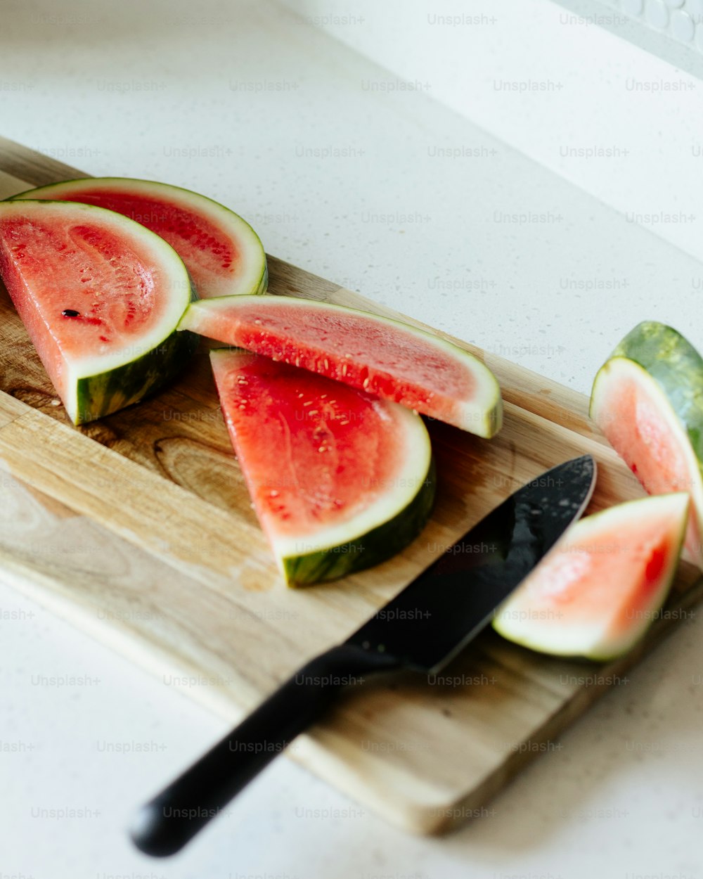 slices of watermelon on a cutting board with a knife