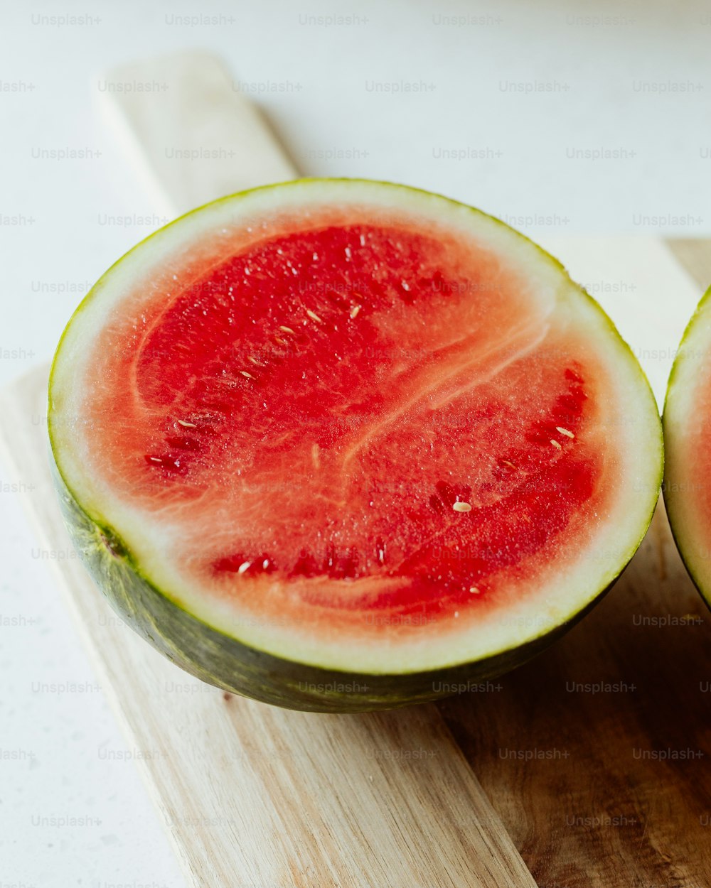 two pieces of watermelon sitting on a cutting board