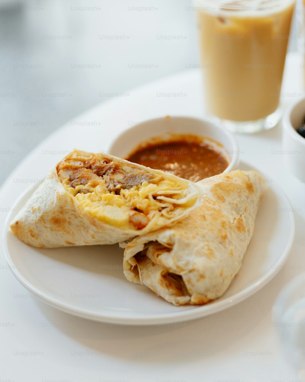 a white plate topped with a burrito and a bowl of salsa