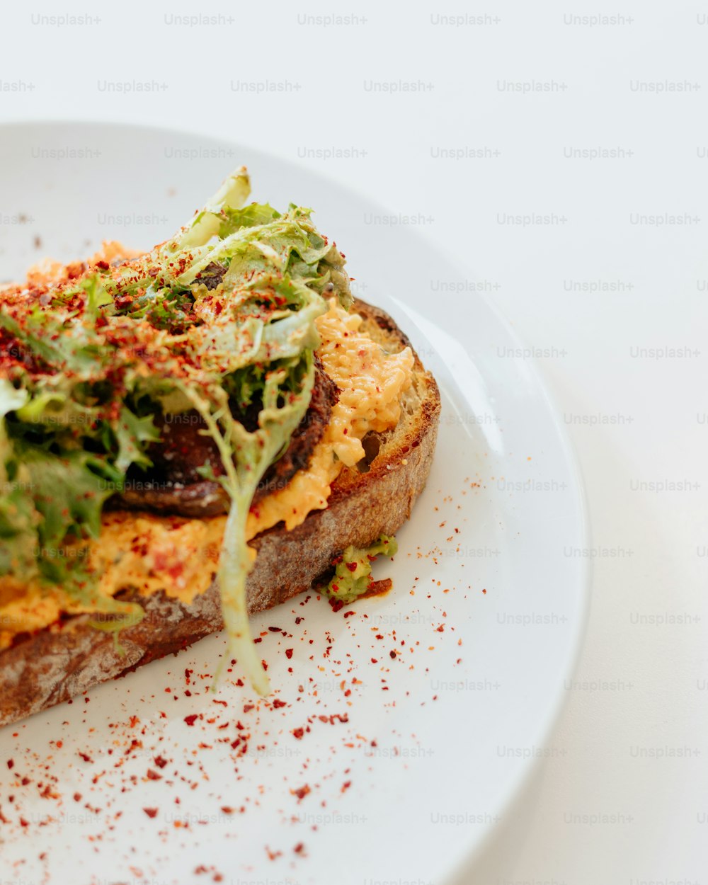 a white plate topped with a piece of bread covered in lettuce
