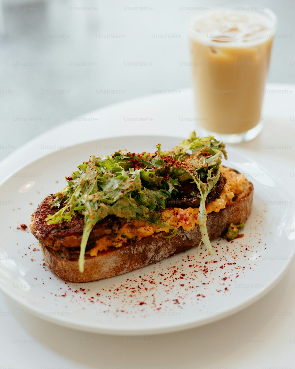 a white plate topped with a sandwich and a drink