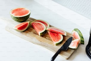 a cutting board with slices of watermelon and a knife