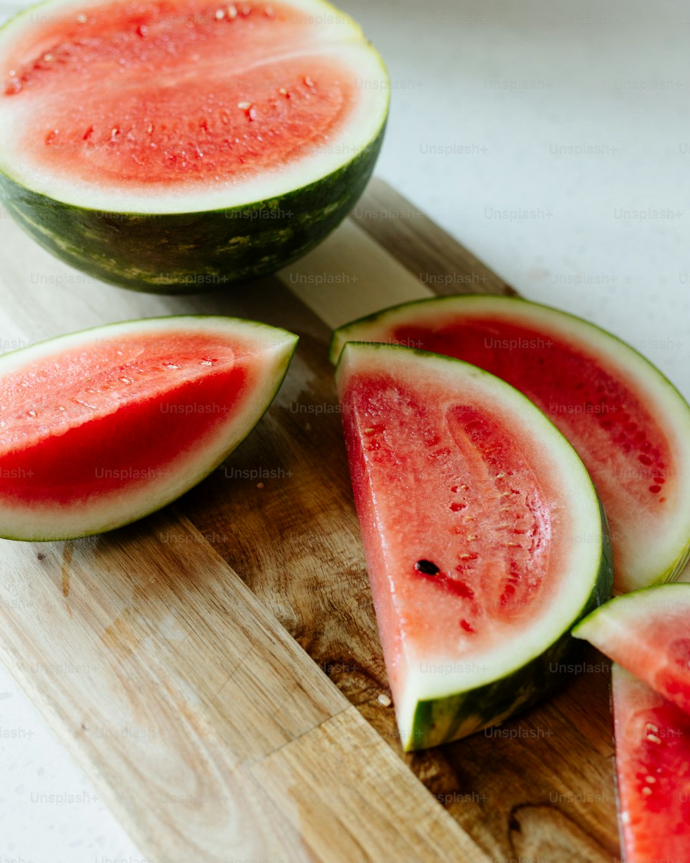 a wooden cutting board topped with slices of watermelon