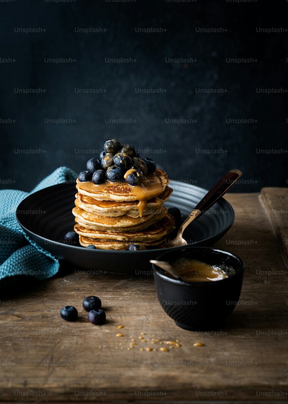 a stack of pancakes with blueberries and syrup