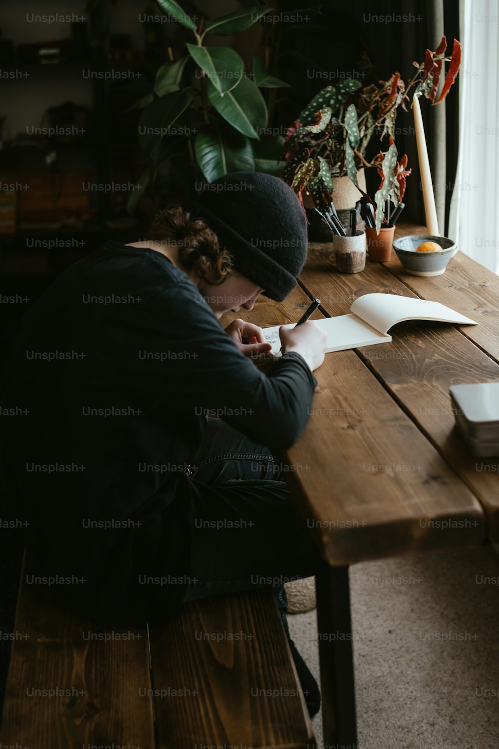 Una persona sentada en una mesa escribiendo en un pedazo de papel