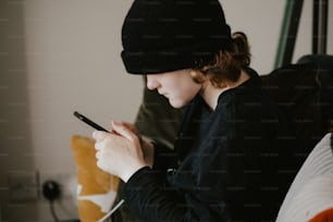 une femme assise sur un lit utilisant un téléphone cellulaire