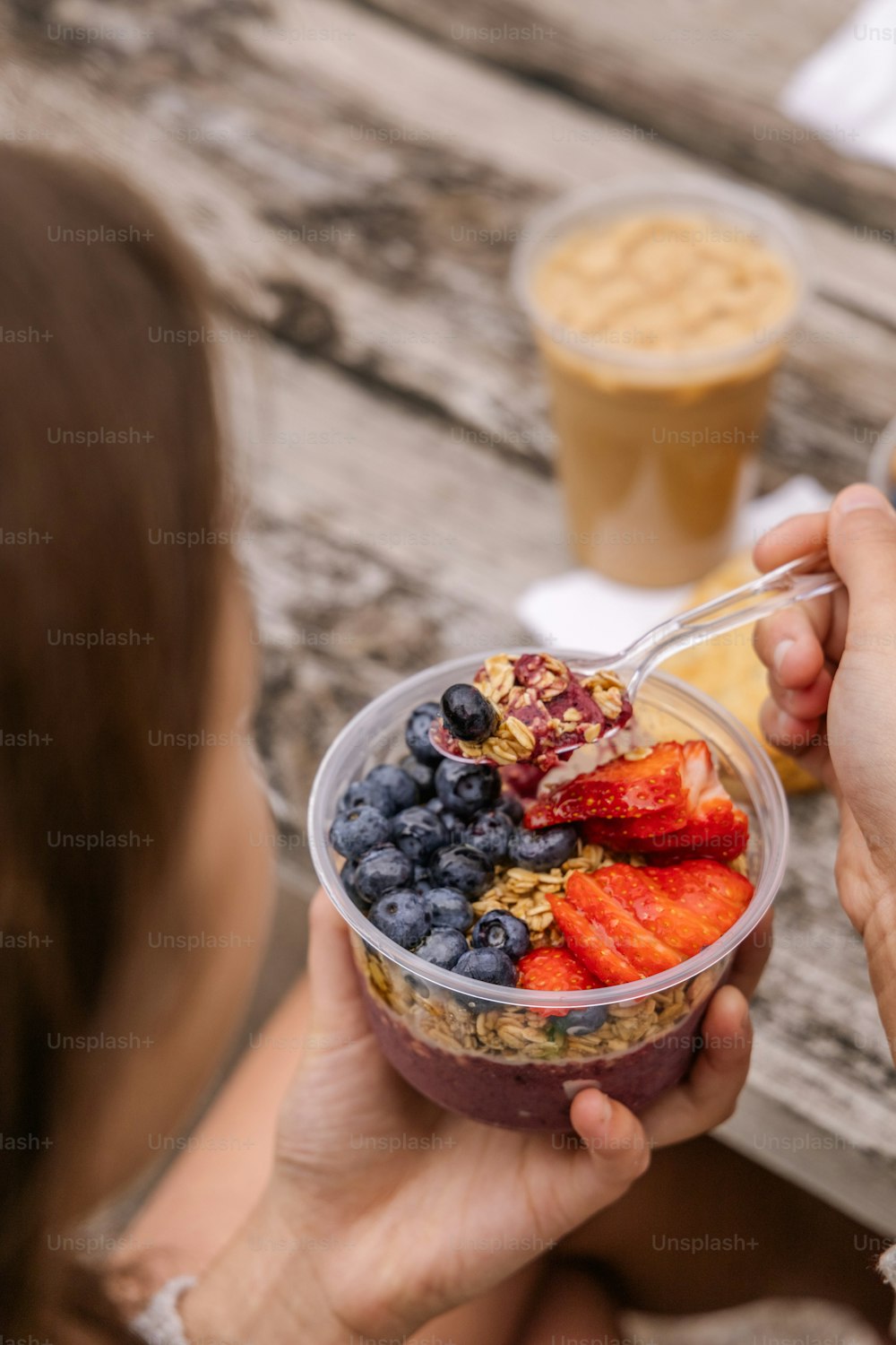 a woman eating a bowl of fruit and yogurt