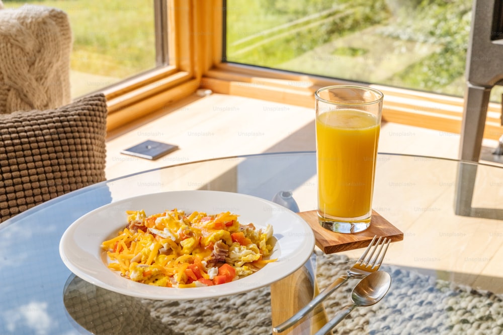 a bowl of food and a glass of orange juice on a table