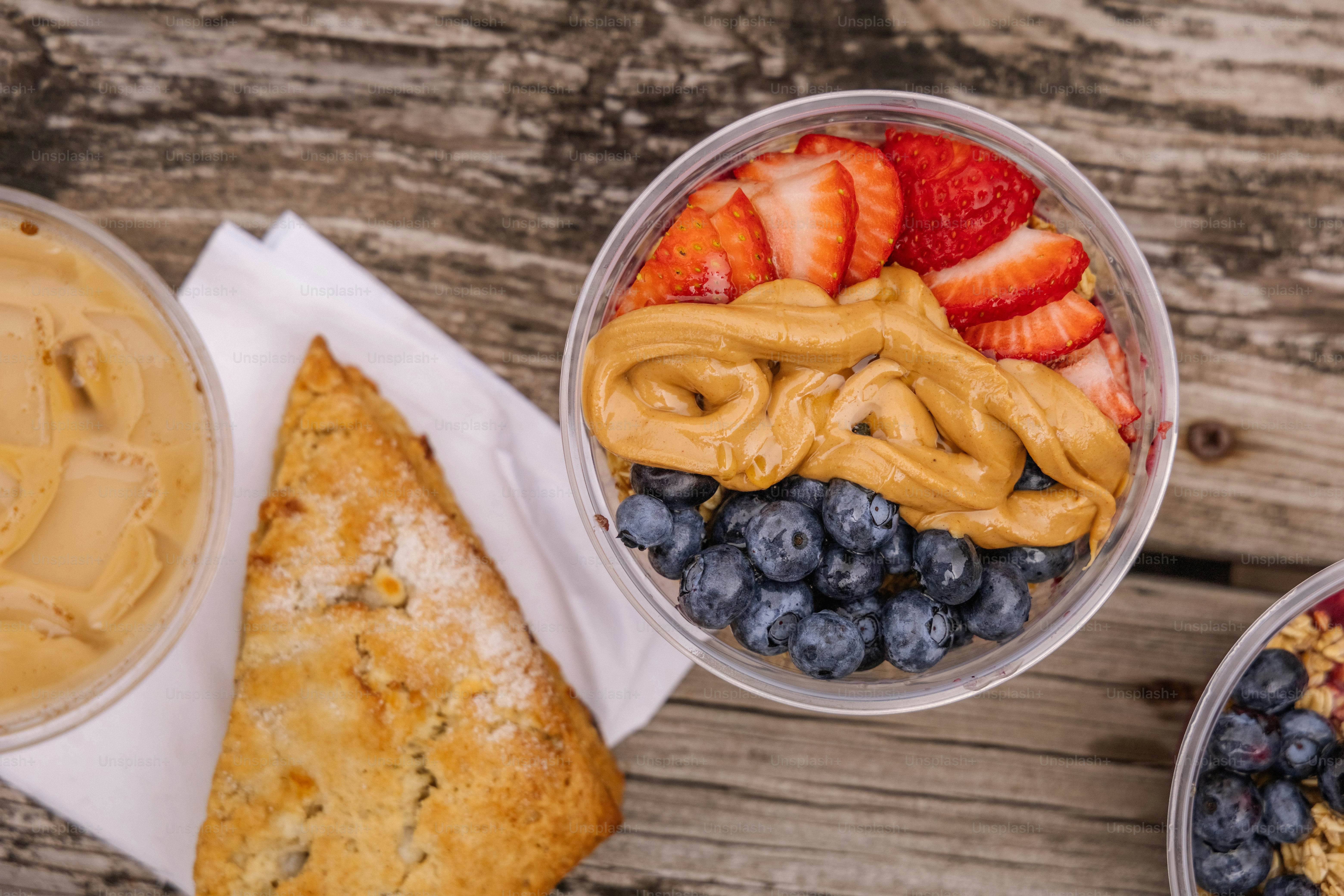 a bowl of fruit and a bowl of peanut butter on a wooden table