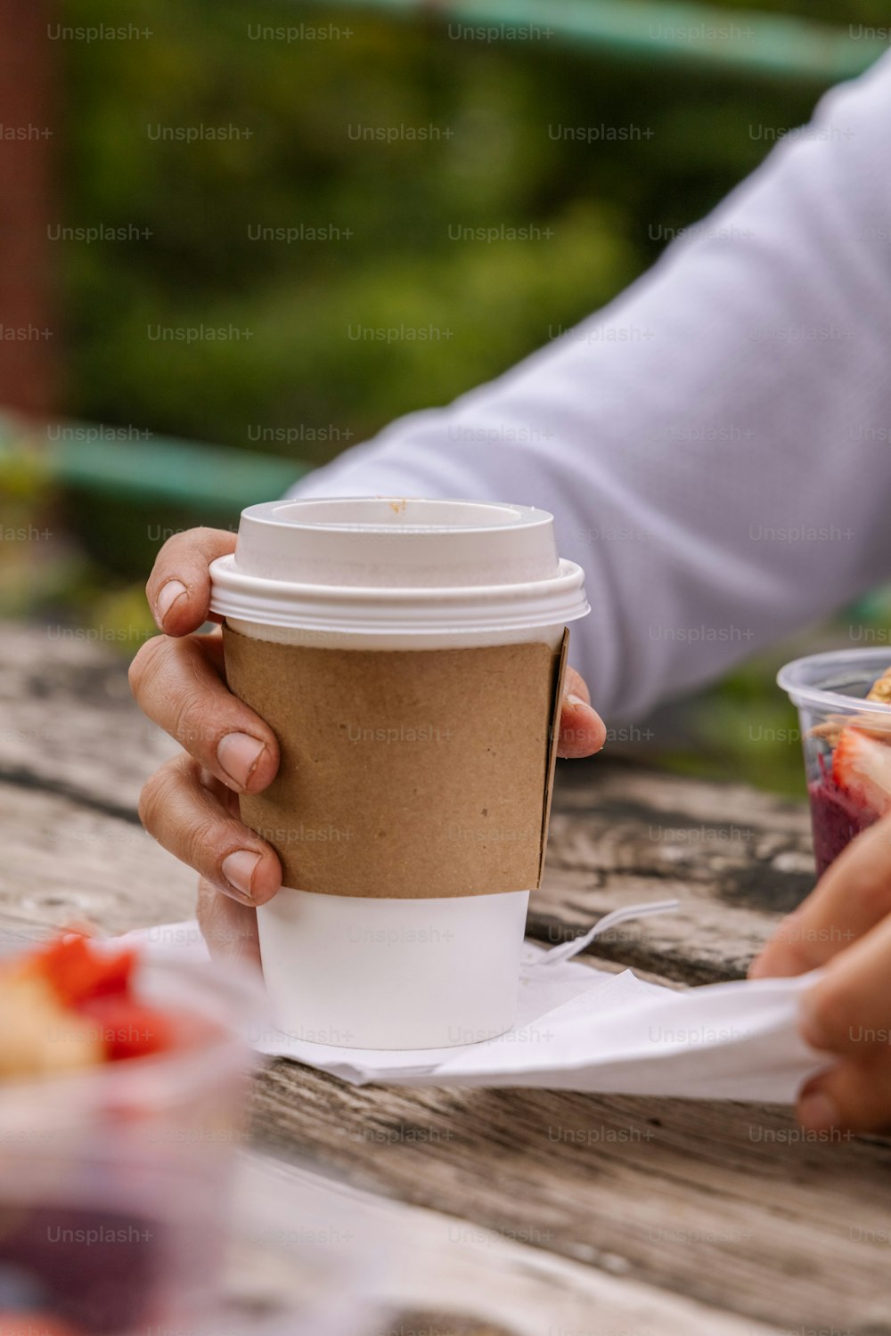 a person holding a cup of coffee on top of a wooden table