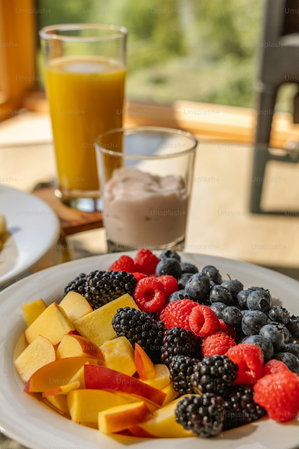 a white plate topped with fruit next to a glass of orange juice