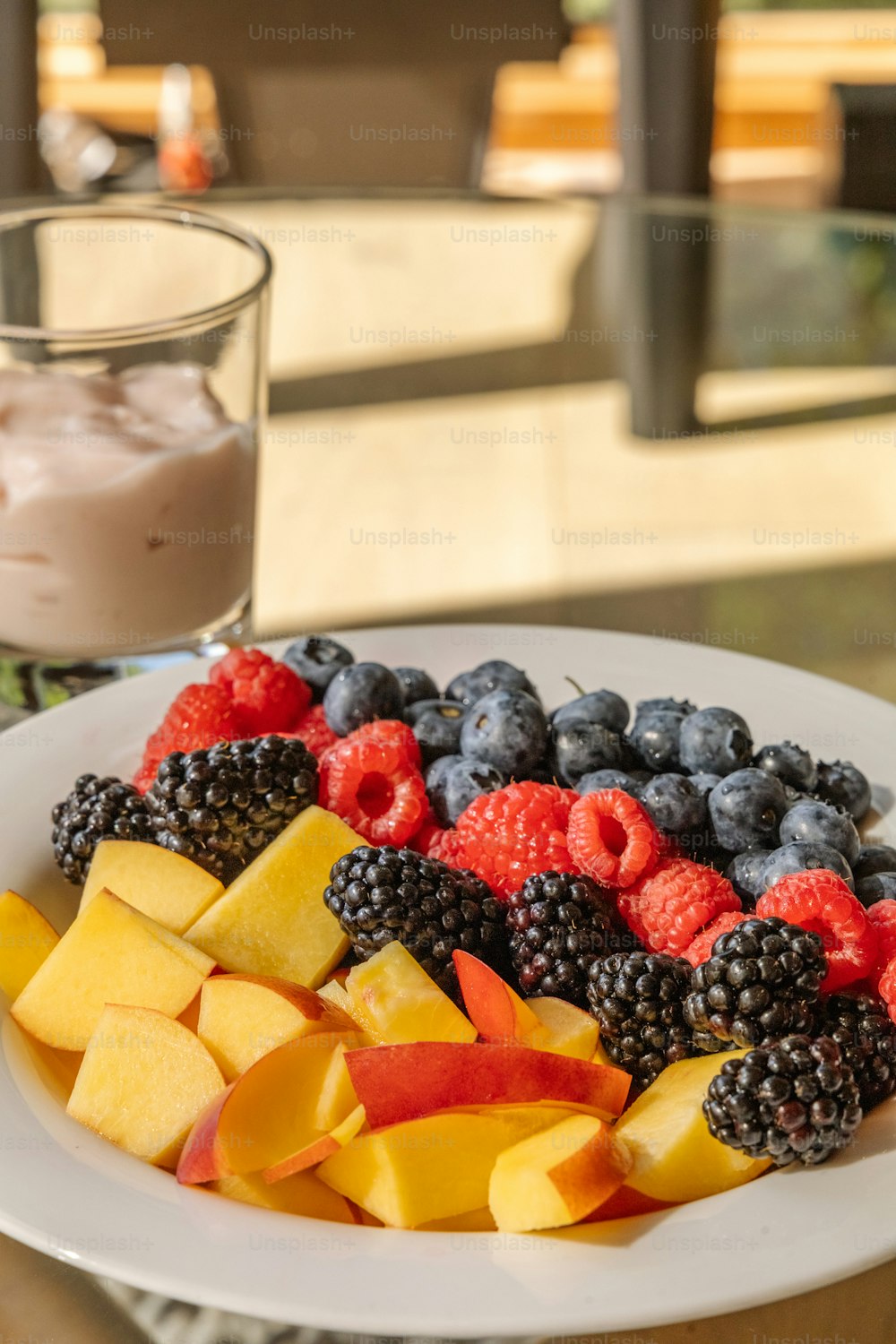a white plate topped with fruit next to a glass of milk