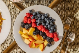 um prato branco coberto com frutas ao lado de uma tigela de frutas