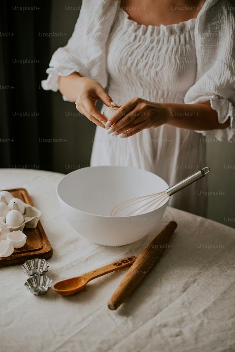 uma mulher em um vestido branco está misturando algo em uma tigela